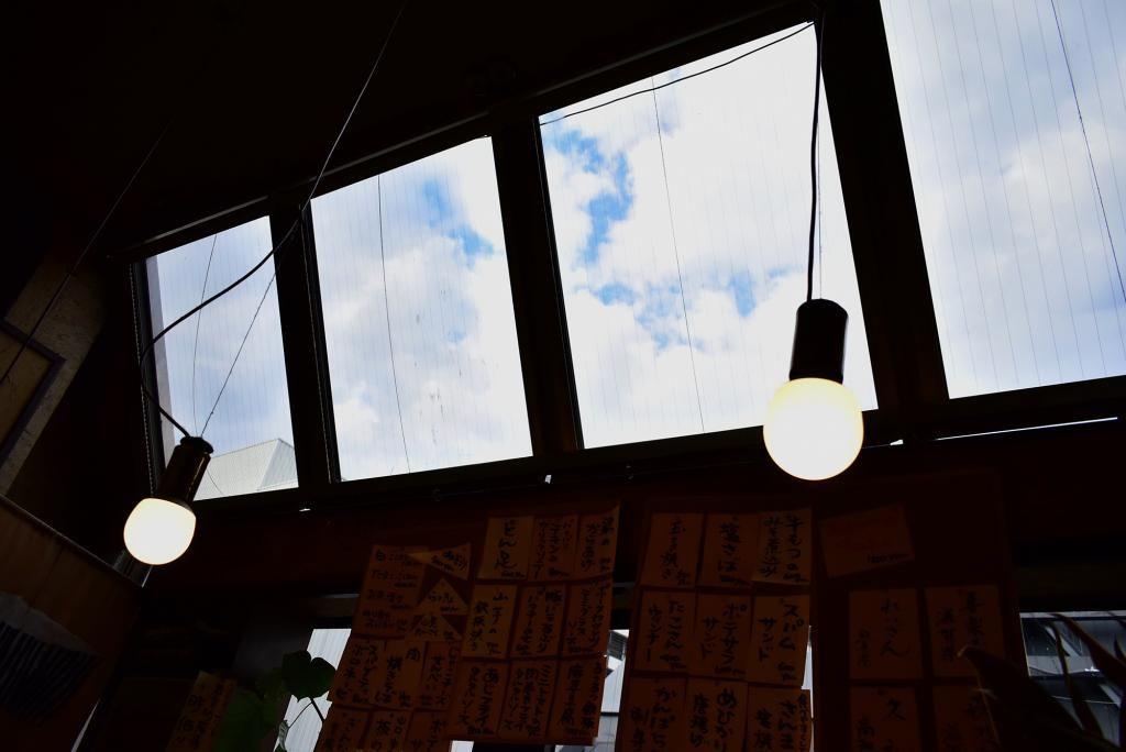 Eine Bar, in der man vom Fenster aus den blauen Himmel sehen kann.